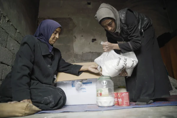 Umm Issa et sa fille Fatima ouvrent le panier de Ramadan d’Islamic Relief. 
