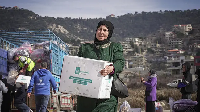 Une mère récupère des articles essentiels pour l’hiver destinés à sa famille, fournis par Islamic Relief.